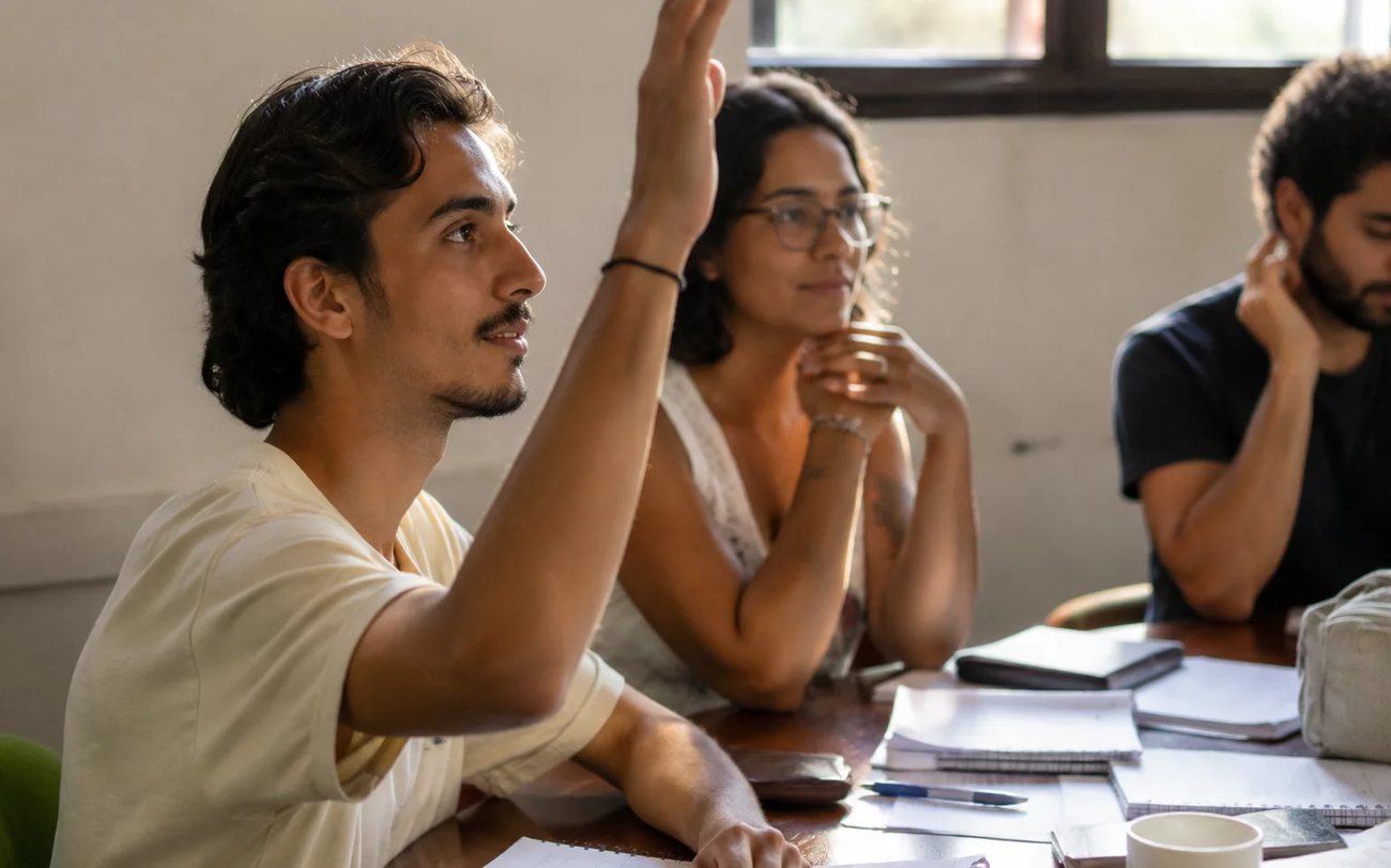 Grupo pequeno reunido em volta da mesa, ouvindo a fala de quem tem a palavra